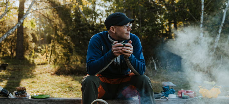Person på bänk vid en eld i skogen