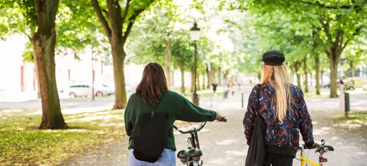 Två personer går och leder cyklar.